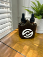 Two dropper bottles in a black sleeve with a partnerco logo on a wooden surface, next to a plant.